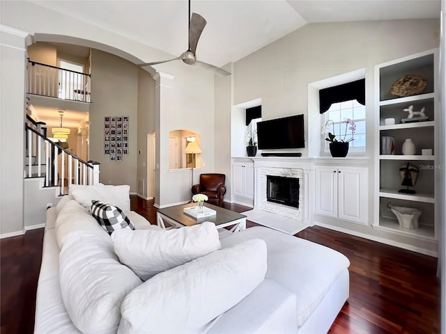 living area featuring stairway, arched walkways, a healthy amount of sunlight, and wood finished floors