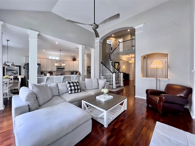 living area with baseboards, decorative columns, wood finished floors, and high vaulted ceiling