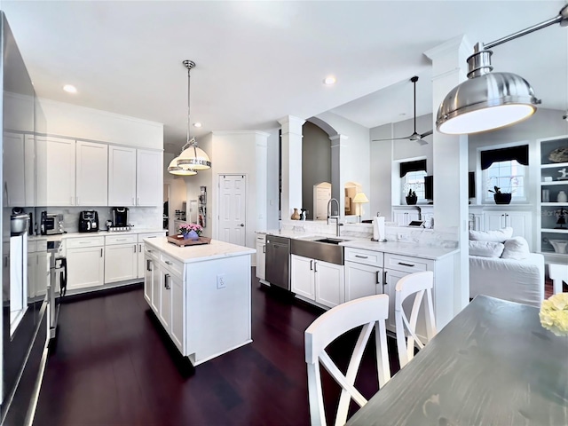 kitchen featuring a sink, decorative columns, tasteful backsplash, dishwasher, and white cabinets