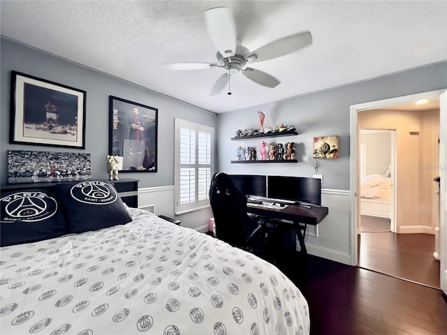 bedroom featuring a textured ceiling, a ceiling fan, baseboards, and dark wood-type flooring