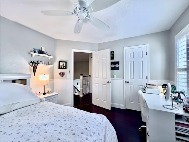 bedroom with ceiling fan, dark wood-style floors, and wainscoting