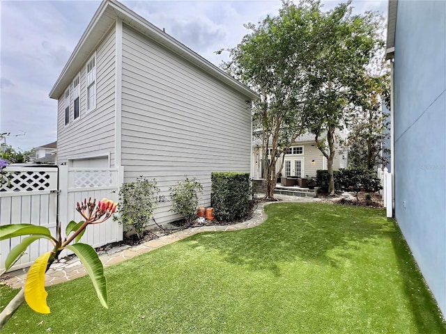 exterior space with a lawn, fence, and an attached garage