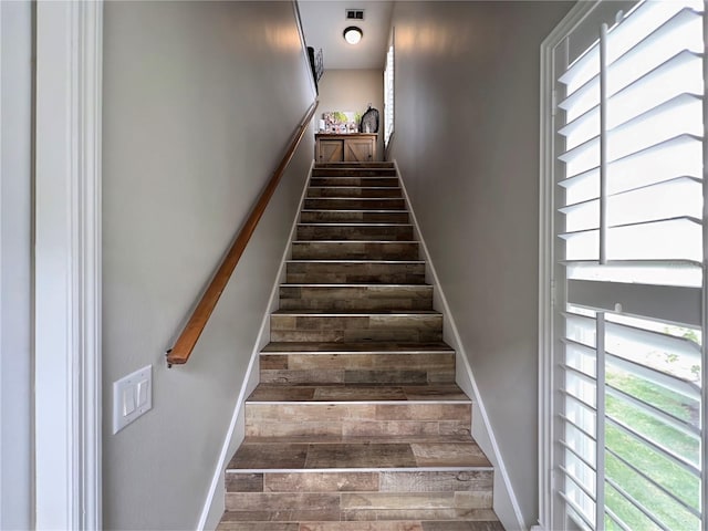 staircase featuring baseboards, visible vents, and wood finished floors