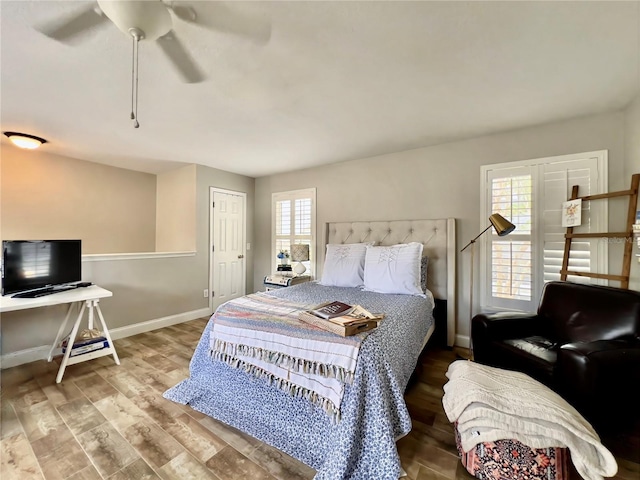 bedroom with ceiling fan, wood finished floors, and baseboards