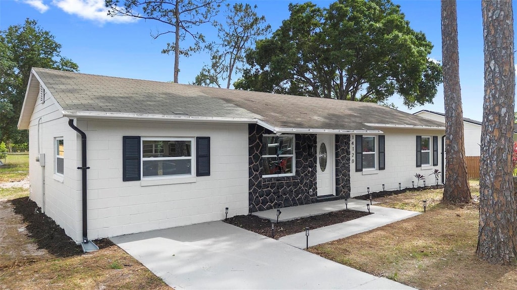 view of front of home with roof with shingles and concrete block siding
