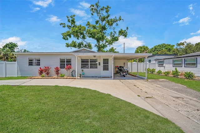 view of front facade with concrete driveway, a front yard, an attached carport, and fence