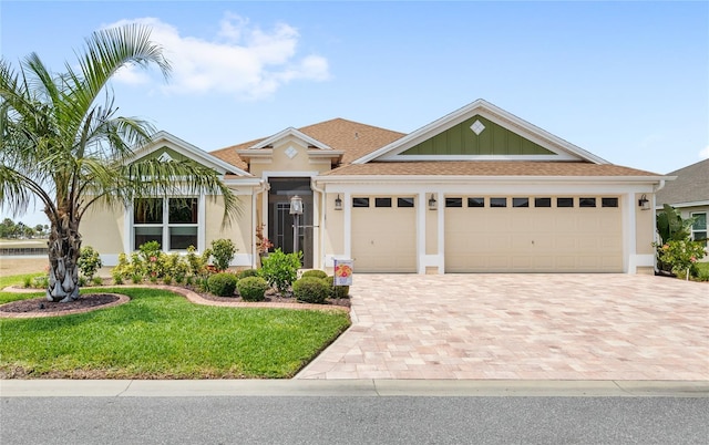view of front of property featuring stucco siding, decorative driveway, a front lawn, and a garage