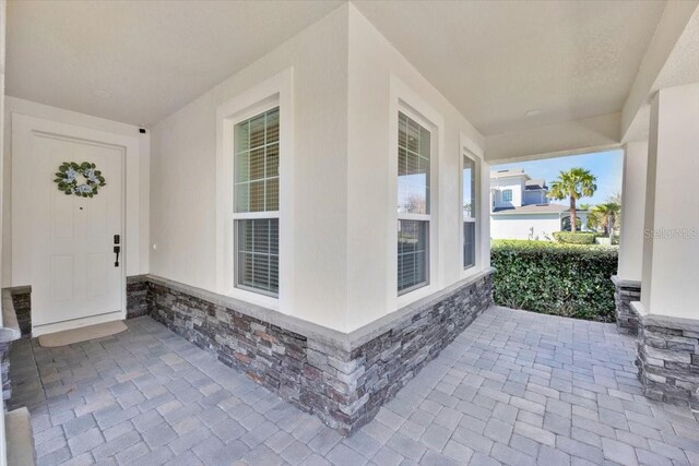 doorway to property with stucco siding and stone siding