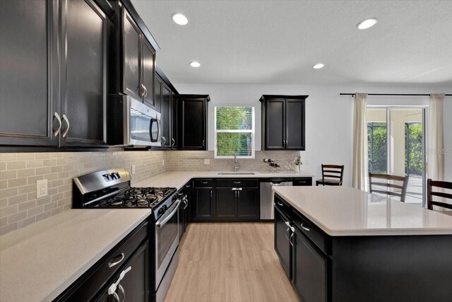 kitchen featuring appliances with stainless steel finishes, a wealth of natural light, dark cabinetry, and a sink