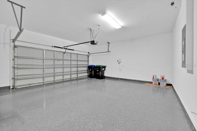 garage with baseboards, a garage door opener, and concrete block wall