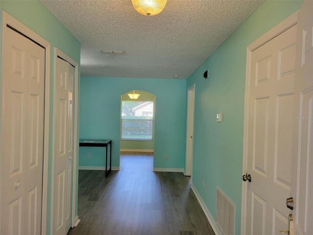 3586 Eversholt St, Clermont, FL 34711 - hallway with dark wood-style floors, arched walkways, a textured ceiling, and baseboards