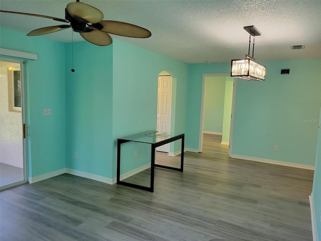 3586 Eversholt St, Clermont, FL 34711 - spare room featuring arched walkways, a textured ceiling, ceiling fan, wood finished floors, and baseboards