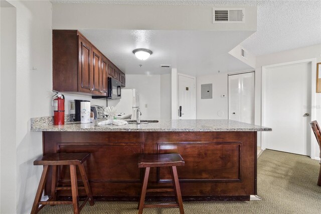 6402 Parc Corniche Dr # 5304, Orlando, FL 32821 - kitchen with a sink, black microwave, a kitchen bar, a peninsula, and visible vents