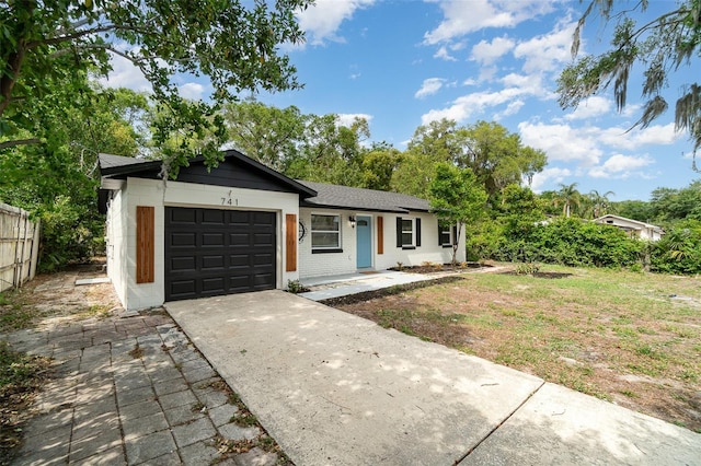 ranch-style house featuring driveway, a garage, and fence