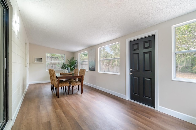 dining area with a textured ceiling, lofted ceiling, wood finished floors, and baseboards