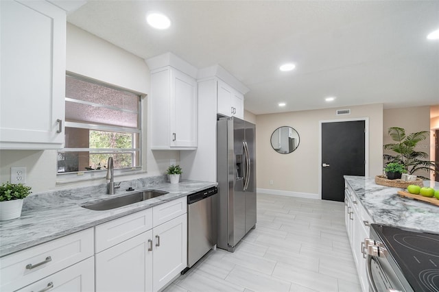 kitchen with light stone counters, stainless steel appliances, a sink, white cabinetry, and visible vents