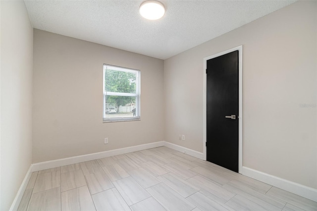 empty room featuring a textured ceiling and baseboards