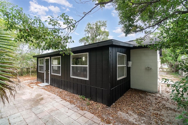 view of property exterior with board and batten siding and a patio area