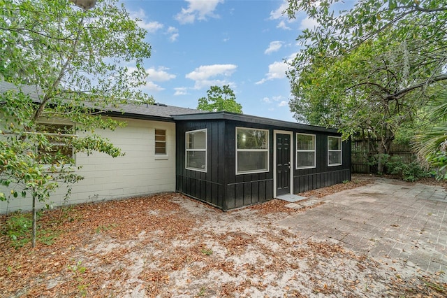 rear view of house with fence, a patio area, and board and batten siding