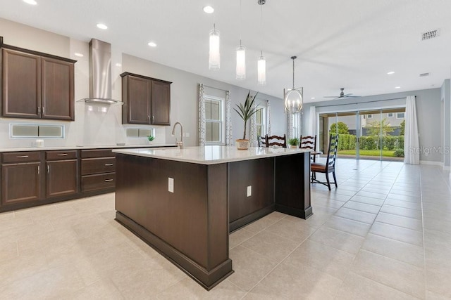 kitchen with visible vents, dark brown cabinetry, wall chimney range hood, light countertops, and a ceiling fan