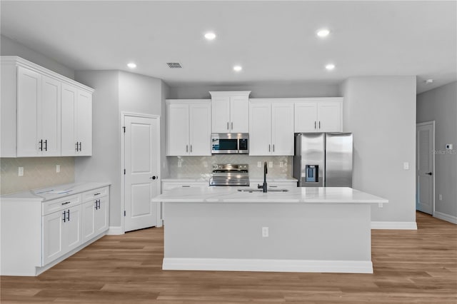13312 SW 41st Ct, Ocala, FL 34473 - kitchen featuring appliances with stainless steel finishes, tasteful backsplash, light wood-type flooring, white cabinets, and recessed lighting