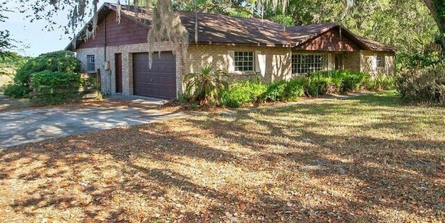 view of front of house with an attached garage, driveway, and brick siding