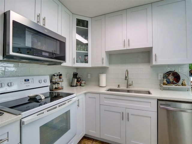 kitchen with appliances with stainless steel finishes, light countertops, white cabinets, and a sink