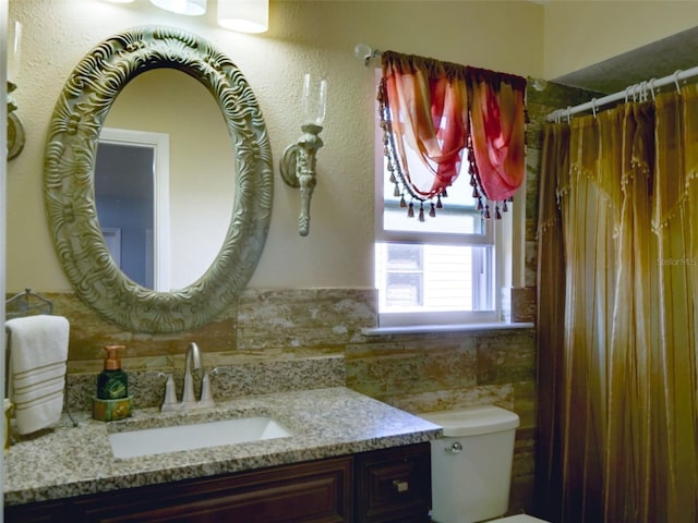 bathroom featuring toilet, curtained shower, vanity, and tile walls