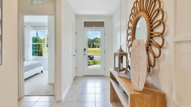 doorway to outside with baseboards, visible vents, and light tile patterned flooring