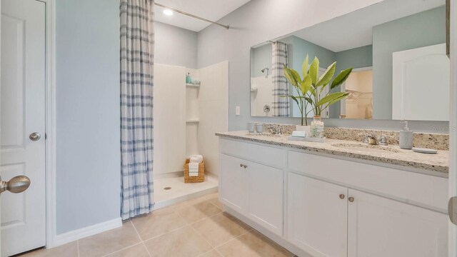 full bath featuring curtained shower, double vanity, a sink, and tile patterned flooring