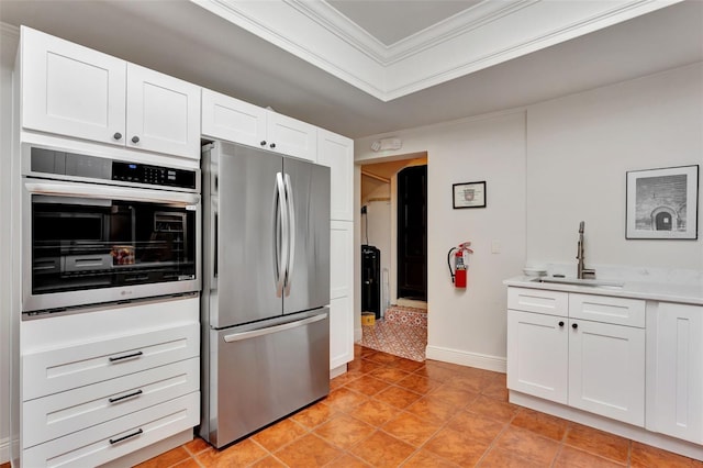 kitchen featuring crown molding, a sink, light countertops, freestanding refrigerator, and white cabinetry