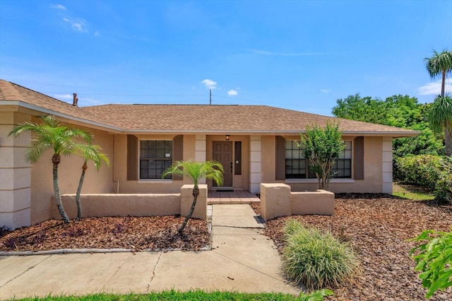 single story home featuring stucco siding, covered porch, and a shingled roof