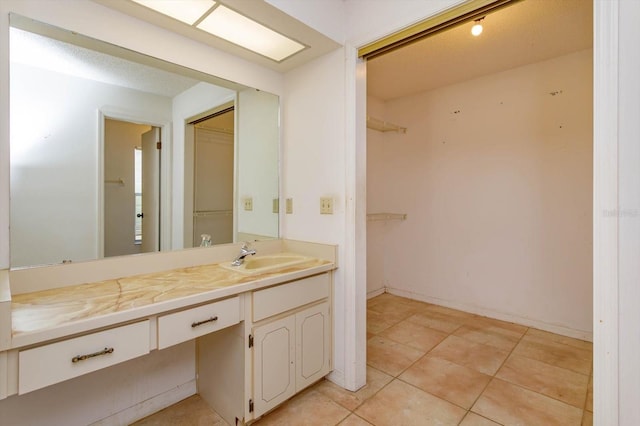 bathroom with tile patterned flooring, vanity, and a spacious closet