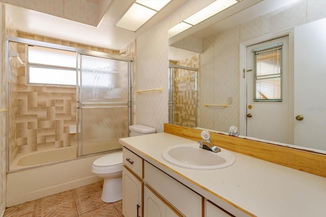 bathroom featuring toilet, bath / shower combo with glass door, a wealth of natural light, and vanity