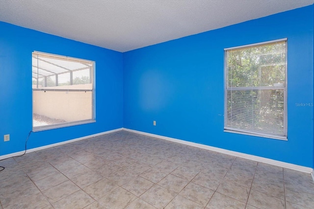 tiled spare room with baseboards and a textured ceiling