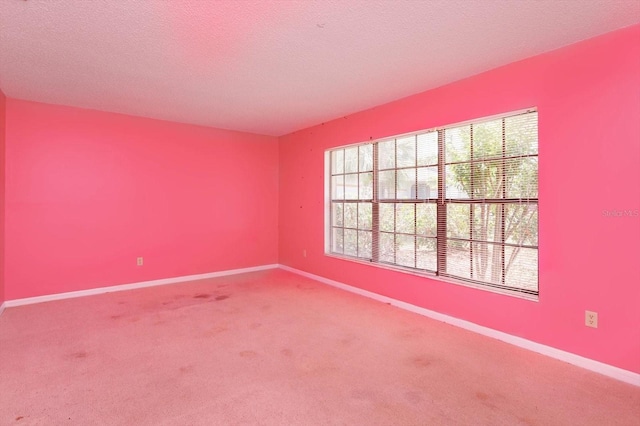 carpeted spare room featuring a textured ceiling and baseboards