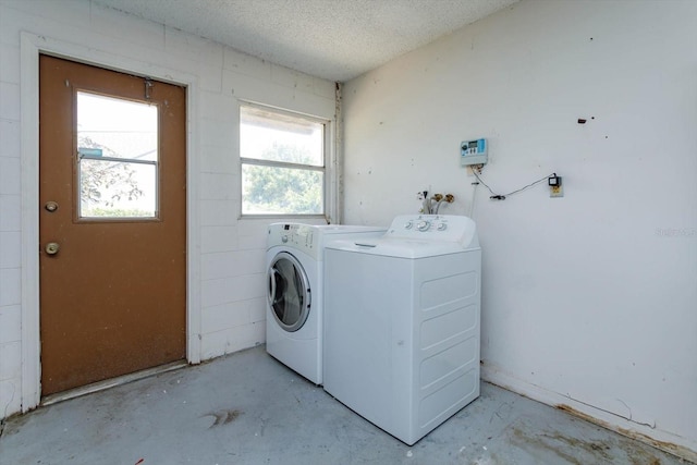 washroom featuring a textured ceiling, washing machine and clothes dryer, and laundry area