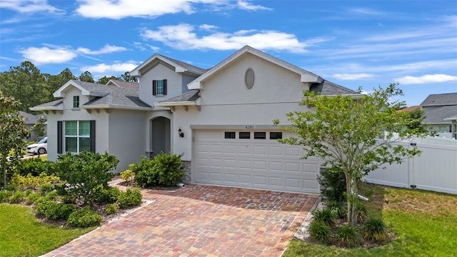 single story home with fence, decorative driveway, stucco siding, a shingled roof, and an attached garage