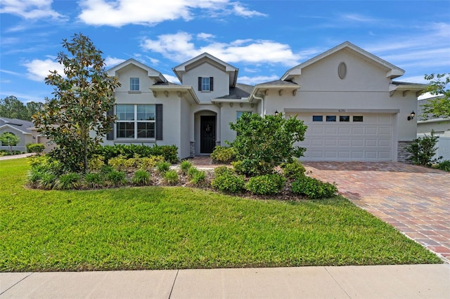 view of front of property with an attached garage, driveway, a front lawn, and stucco siding