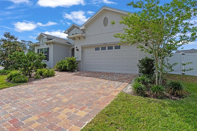single story home featuring an attached garage, decorative driveway, stucco siding, and fence
