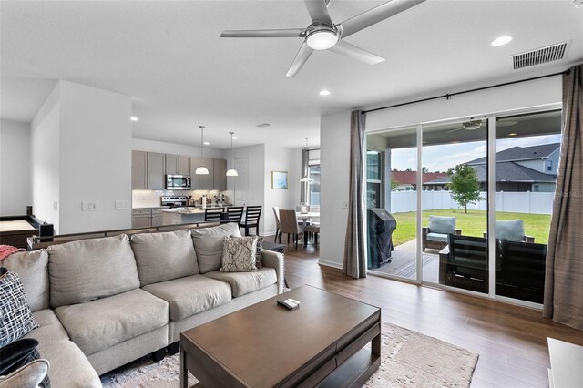 living area with light wood-style floors, a ceiling fan, recessed lighting, and visible vents
