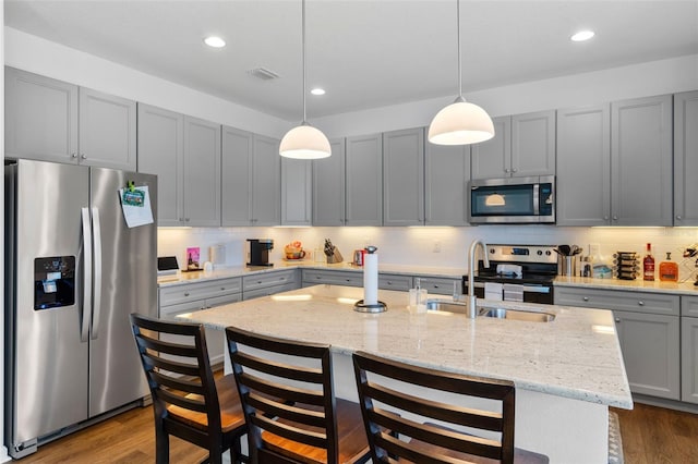 kitchen featuring a sink, appliances with stainless steel finishes, gray cabinets, and dark wood-style flooring