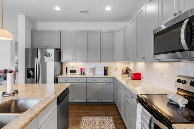 kitchen featuring light stone countertops, stainless steel appliances, backsplash, visible vents, and dark wood-style floors