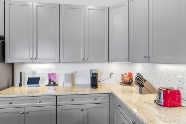 kitchen with light stone countertops, gray cabinetry, and tasteful backsplash