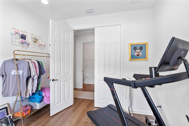 exercise area with baseboards, visible vents, and wood finished floors