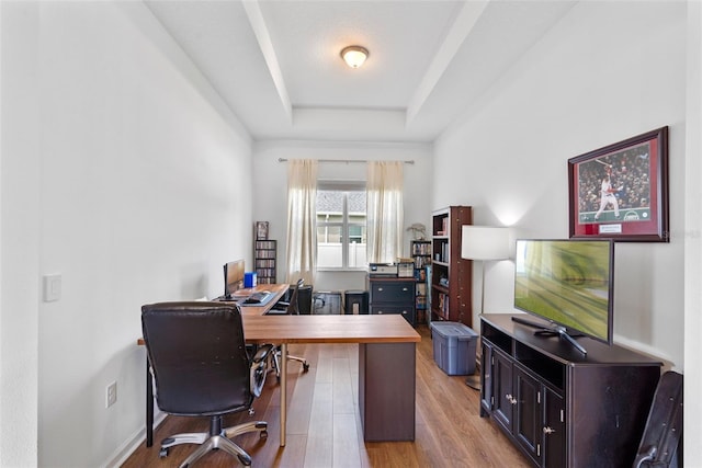 office area featuring light wood-style floors and a tray ceiling