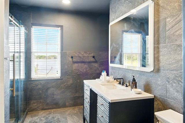 full bath with tile walls, a stall shower, and vanity