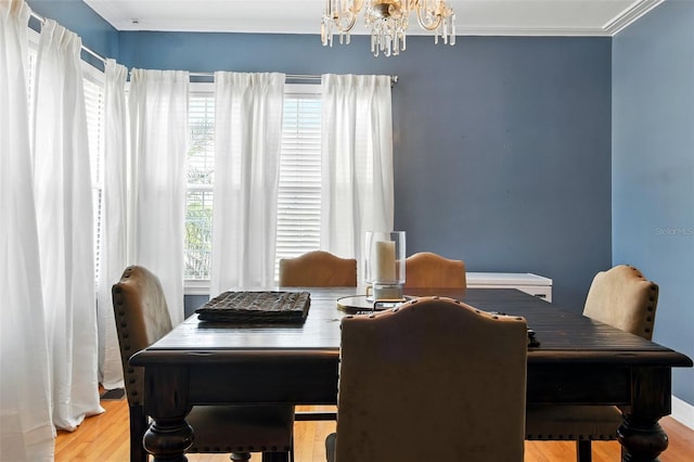 dining room featuring wood finished floors, crown molding, and a notable chandelier