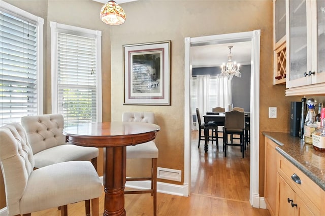 dining room featuring light wood finished floors, visible vents, a chandelier, and baseboards