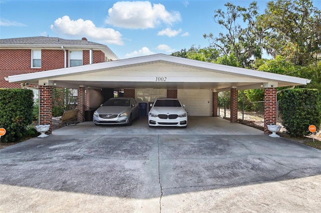 view of vehicle parking featuring driveway, a carport, and fence